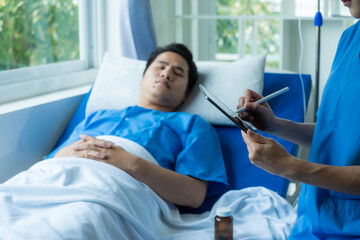 An Asian male patient lies in a hospital bed and is carefully looked after by a doctor. Doctor giving advice to male patient Working on health disease diagnosis