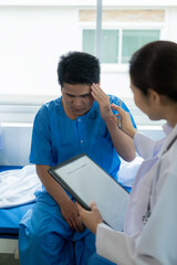 Fototapeta premium An Asian male patient lies in a hospital bed and is carefully looked after by a doctor. Doctor giving advice to male patient Working on health disease diagnosis