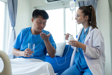 An Asian male patient lies in a hospital bed and is carefully looked after by a doctor. Doctor...