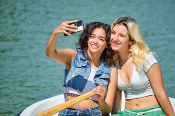 multiethnic young lesbian couple taking a selfie in a rowboat on a lake on a sunny day