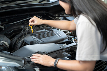 Woman standing next to a car with the hood up, checking the engine.