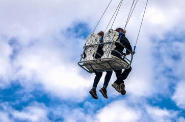 children ride on a carousen on a background of blue sky and white clouds