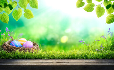 Three painted easter eggs in a birds nest celebrating a Happy Easter in spring with a green grass meadow, tree leaves and bright sunlight background with copy space & wooden bench to display products.