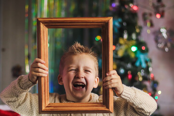 portrait of a cute boy of European appearance in a wooden picture frame against the backdrop of a...