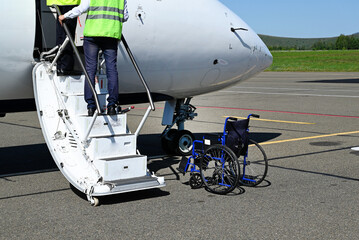 Wheelchair patients Airport, Disabled person in the interior of the airport with airplane being preparing ready for taking off in back. © Svetlana Verbitskaya