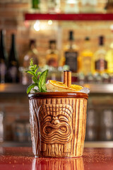 Refreshing cold Tiki cocktail on the bar. Summer party background.