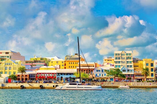 Catamaran passing pastel coloured buildings on Front Street, Hamilton, Bermuda, Atlantic