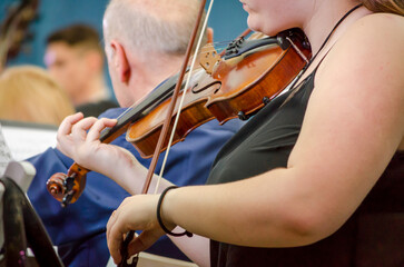 female musician playing a violin with a symphony orchestra