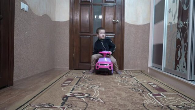 the boy drives a car in the room, brother and sister play together in the room, happy children at home
