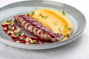 Duck breast, with pumpkin puree, cherry sauce and peanuts. Isolated image