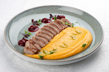 Duck breast, with pumpkin puree, cherry sauce and peanuts. Isolated image