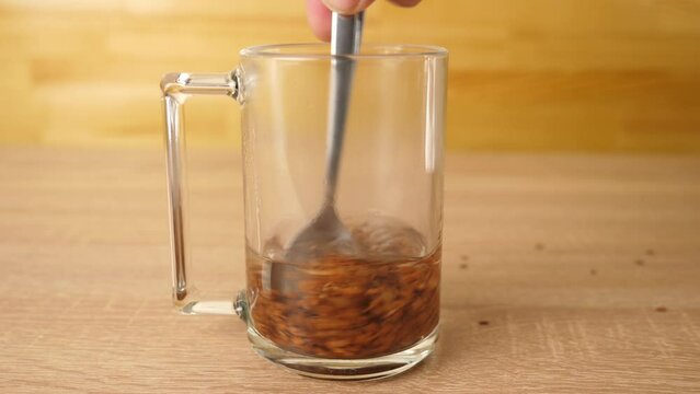 .To prepare a therapeutic decoction, flax seeds are shaken in a glass of boiling water.