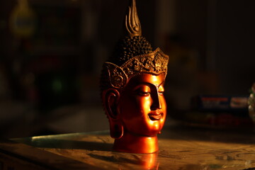 A Red and brown colored Buddha Statue or figurine in golden hour sunlight with selective focus,...