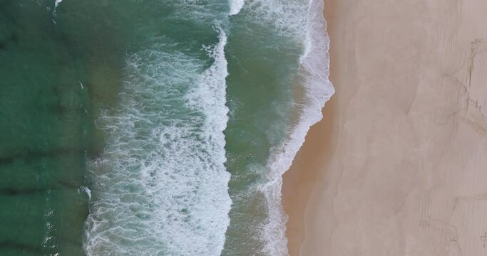 Aerial drone shot of shoreline with ocean waves breaking on Praia da Aberta Nova beach, Alentejo Coast, Portugal, Europe. Shot in 5k, ProRes 422HQ, exported in ProRes. Nature and organic textures 