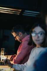 Multicultural business team collaborates late into the night, analyzing data and discussing strategies for success.