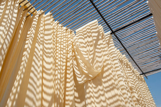 Washed bolts of cotton fabric hanging to dry on bamboo structure before being hand block printed, Bagru, Rajasthan, India