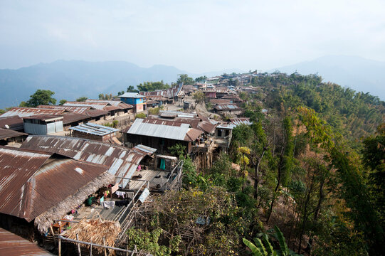 Naga village houses clinging to the hillside leading up to Baptist church at the top, Chanlangshu village, Nagaland, India