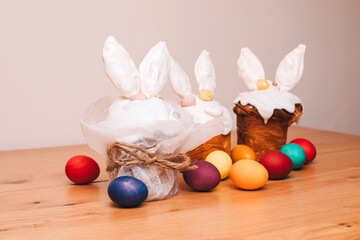 Easter cake is decorated with white meringue with ears and chocolate eggs on a wooden table. Easter background, preparation for the celebrate table. Front view