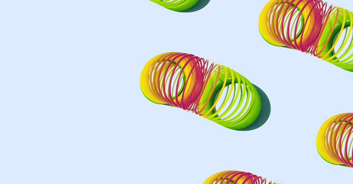 Flexible rainbow children's retro toy on a pale blue background. Slinky. Anti-stress toy. Vintage aesthetic. Flexibility symbol. Nostalgia concept. Space for text. Banner, header
