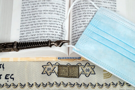 A silver Yad Jewish ritual pointer on a Torah and surgical mask, France