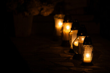 Night shot of the flames of glass cemetery candles standing on tombstones. The shot was taken...