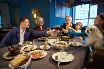 Fototapeta na wymiar Family holding glasses of wine celebrating winter holiday together in restaurant