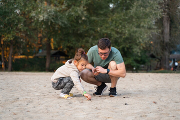 Fototapeta premium Father with child girl playing on the riverside, happy modern involved fatherhood. 