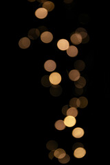 Blurred lights festive garland on a black background. Bokeh golden lights