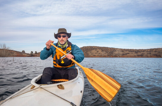 senior male in life jacket is paddling expedition canoe, cold season scenery on Horsetooth Reservoir in northern Colorado, POV from action camera