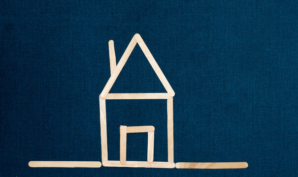 simple house drawn with ice cream sticks with blue background