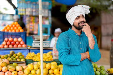Young Indian fruit seller selling or showing his fruit - obrazy, fototapety, plakaty