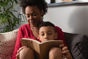 Young boy reads book together with mother in home room