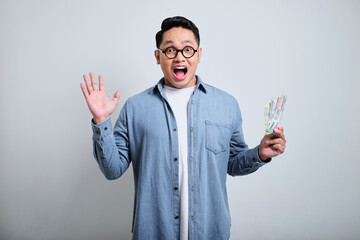Portrait of handsome young asian man wearing denim and glasses in the smile face holding money and...