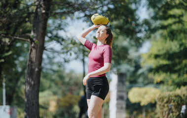 Active and fit young women in a park, playing and exercising together. Their sunny day workout involves throwing a rugby ball and enjoying the outdoors.