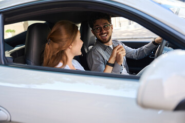 Excited and smiling woman holding hands and looking at each other in automobile