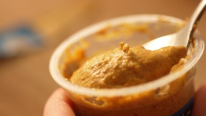 Spoonful of Mustard Over Container, Kitchen Scene. Close-up, shallow dof.