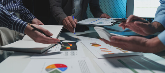 Group of business people meeting, discussion, brainstorming, pointing at graphs and charts to analyze market data, calculating balance sheets, accounts, net profits to plan company sales strategies. - obrazy, fototapety, plakaty