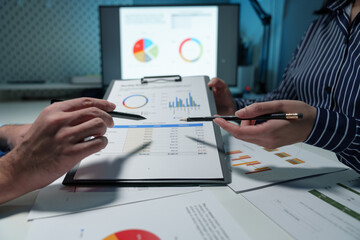 Group of business people meeting, discussion, brainstorming, pointing at graphs and charts to analyze market data, calculating balance sheets, accounts, net profits to plan company sales strategies.