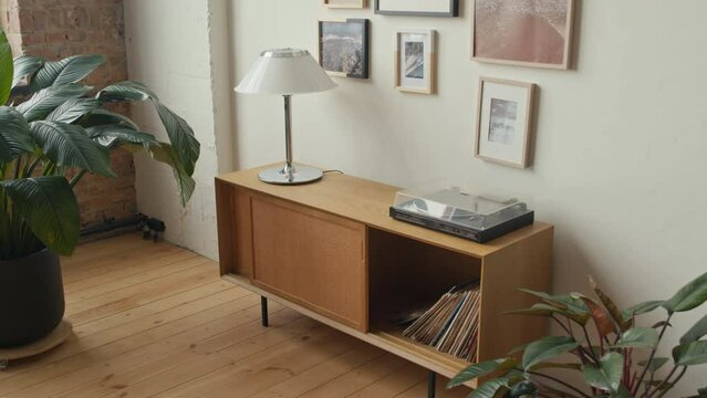 Vinyl record cabinet with player and lamp in cozy living room with mid-century modern style interior