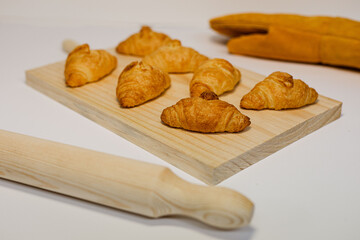 Fotografía de producto de pastelería de varios Mini Croissants en una tabla de madera sobre fondo...