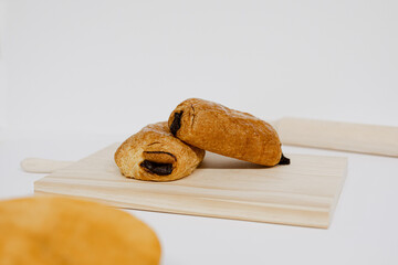 Napolitanas de chocolate y crema en una tabla de madera sobre fondo blanco. Fotografía de producto de panadería - obrazy, fototapety, plakaty