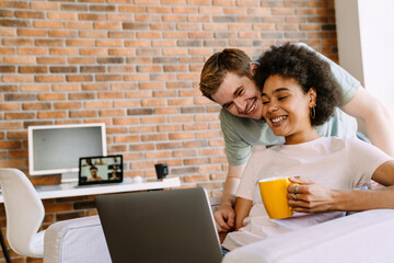 Happy couple looking at laptop screen while working remotely in home office