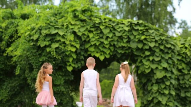 Boy and two girls in white clothes go away on walkway