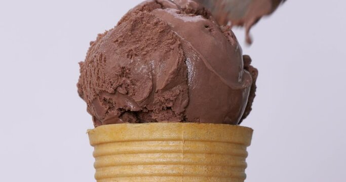 Scoop chocolate ice cream into the cone on a white background.