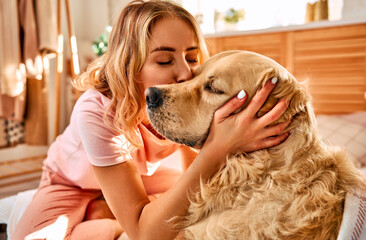 Cozy domestic moment. Caring young woman embracing and kissing with love her furry pet companion at...