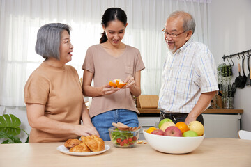 asian family senior couple and granddaughter enjoy cooking salad and peel an orange in the kitchen