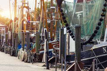 Traditional old german fishing cutter boats moored Neuharlingersiel harbor Wadden sea East Frisia Northern Germany. Commercial fish crab shrimp trawler beam trawl nets North Sea small port city - obrazy, fototapety, plakaty