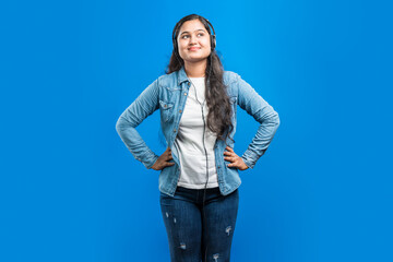 Portrait of a beautiful Indian girl enjoying music through headphones and keep her hand in her waist