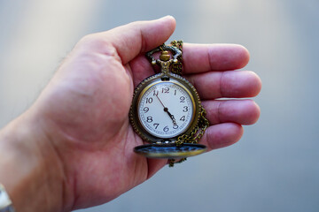 Close up hand holding gold pocket watch, blurred copy space background, saving and manage time to success business, relaxation and lifestyle concept