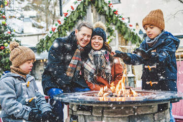 Obraz premium family with two little son having fun together outdoor on frosty day close to a fire